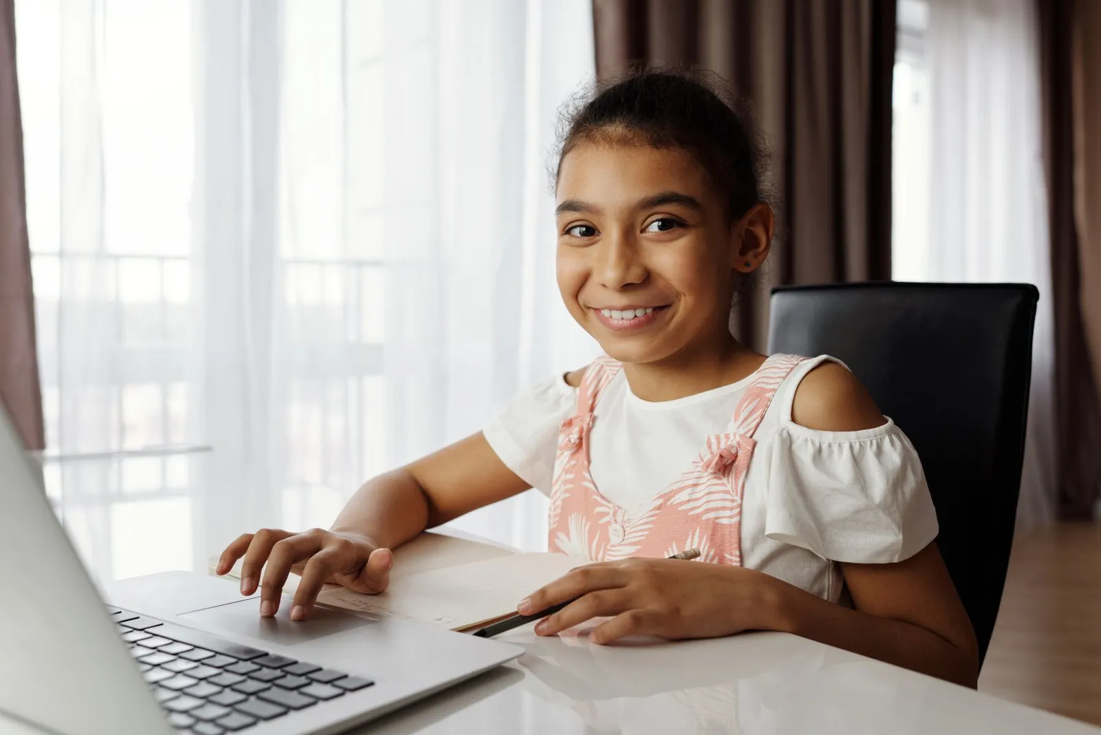 A young girl smiling while building a project on her laptop